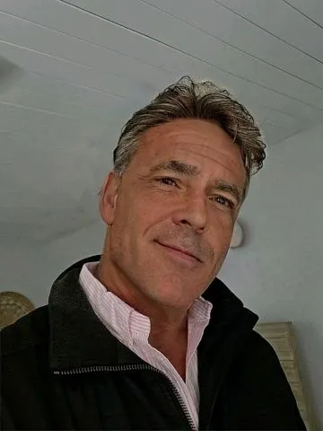 A man with grey hair and wearing a black jacket.
